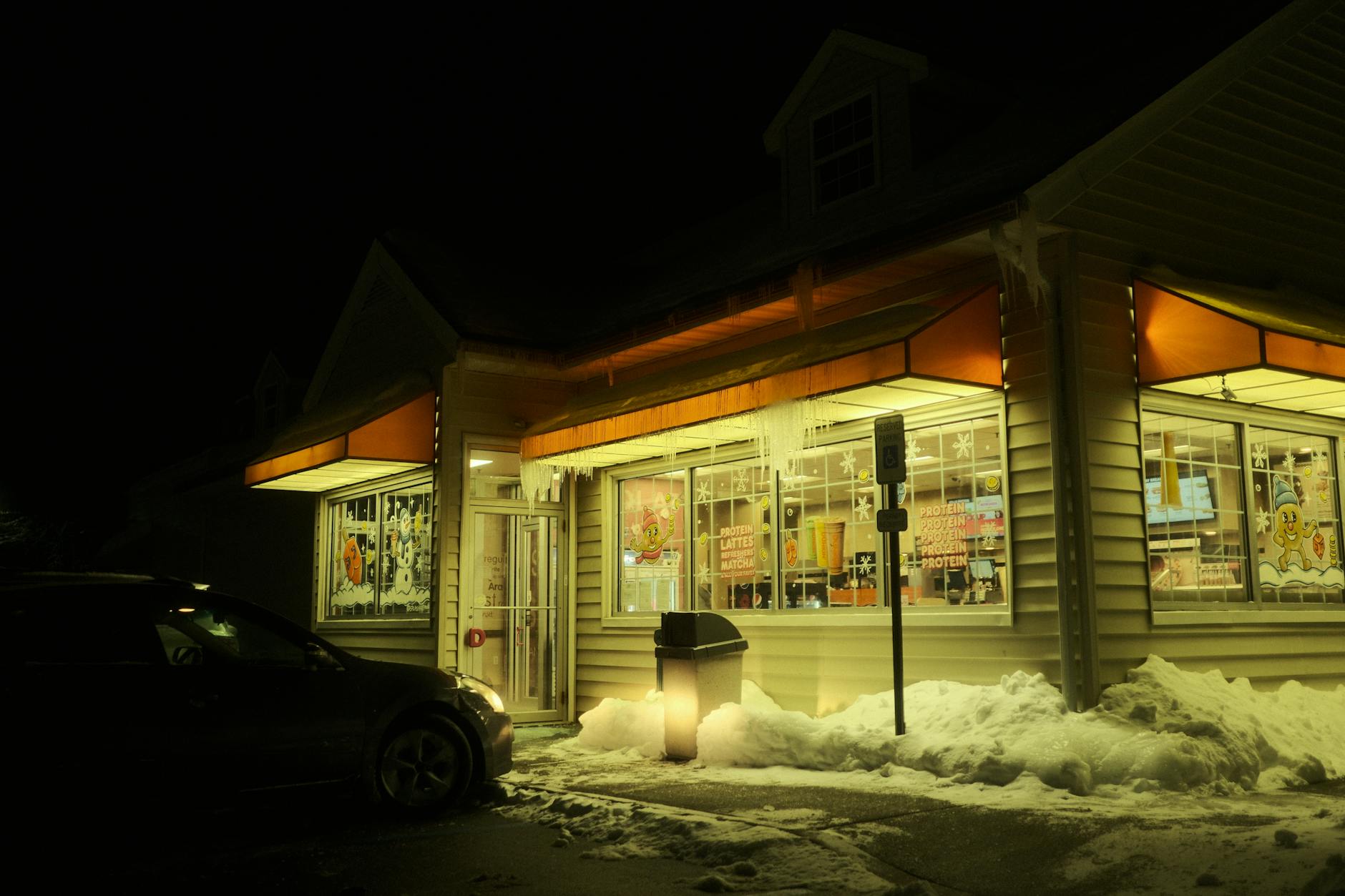 A convenience store at night with snow and icicles, illuminating the street in winter.